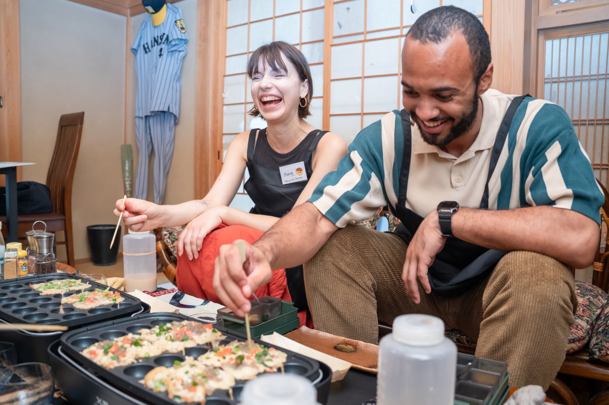 Guests smiling and enjoying their homemade takoyaki at Tako no Ma